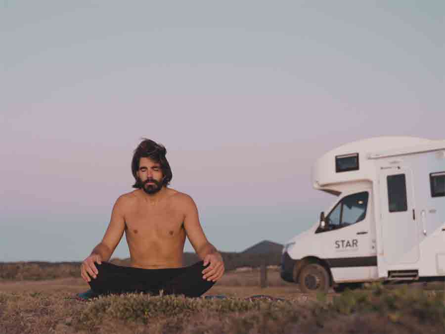 Man meditating on grass outside Star RV motorhome