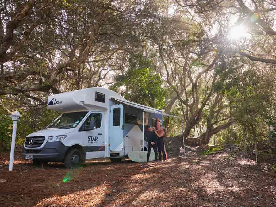 Man putting on wetsuit outside motorhome